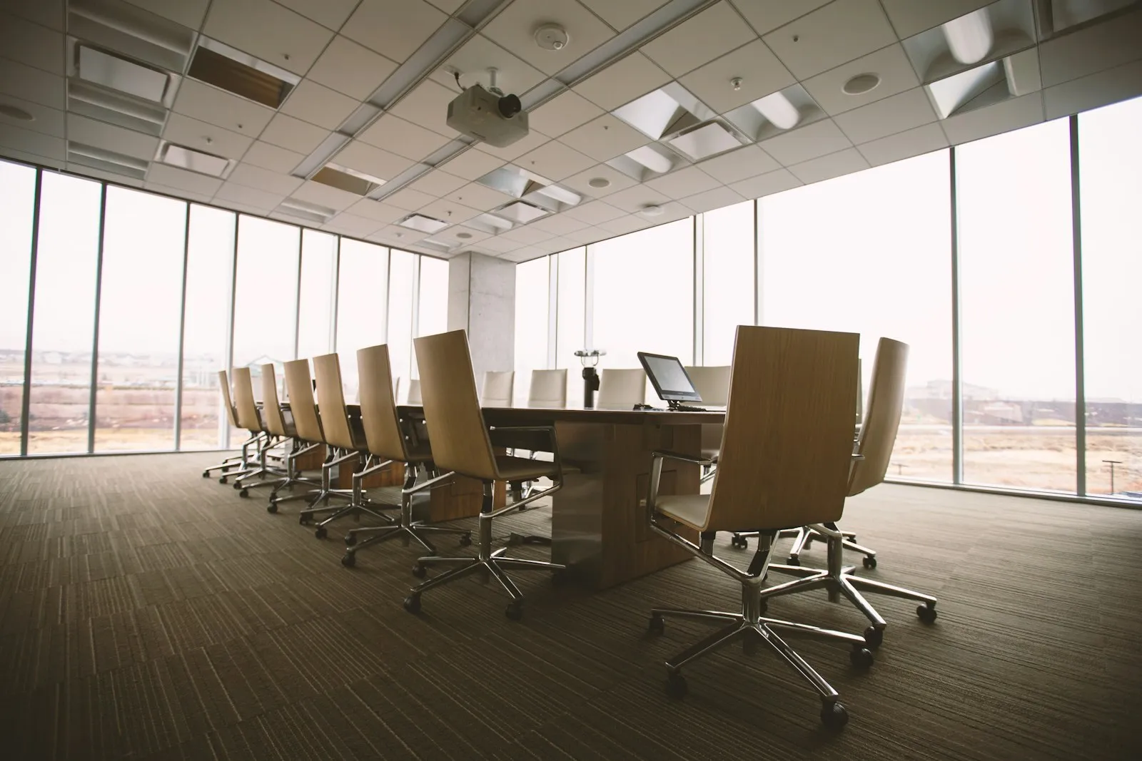 An empty conference room with a long wooden table and office chairs